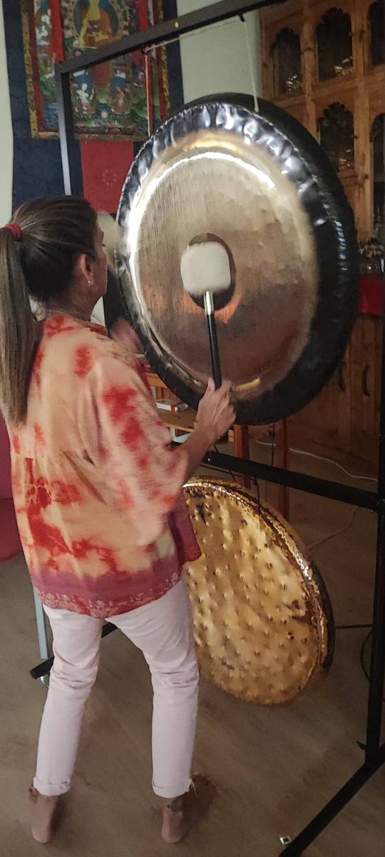 Montse tocando el gong junto a un thangka
