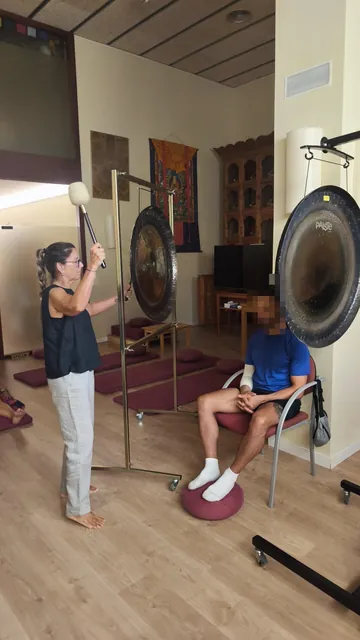 Baño de sonido individual: Montse Terradas toca el gong planetario junto a una persona sentada
