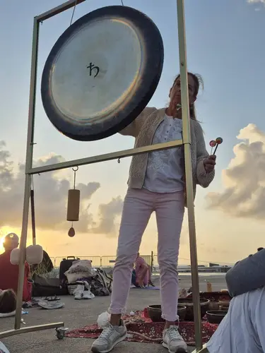 Montse tocando el gong al atardecer junto al mar