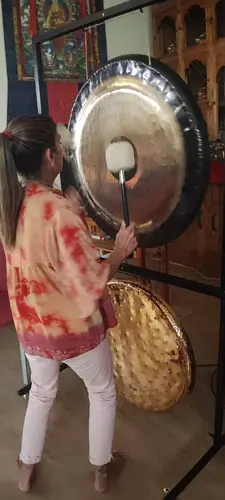 Montse tocando el gong junto a un thangka