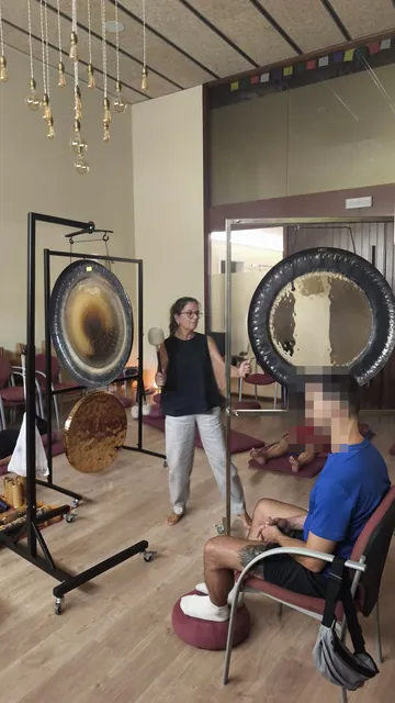 Sesión de gong en la sala con luz cálida, gongs planetarios y participantes